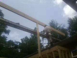 Carpenter setting a ridge beam over a new addition frame — Ice Dam Removal by Roofing Brothers in Shallotte