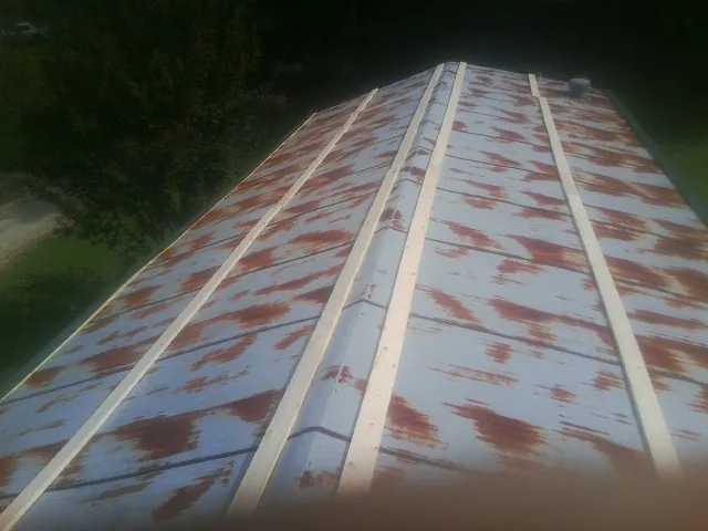 Rusted metal roof panels with new wood purlins before replacement — Storm Damage Roof Repair in Shallotte by Roofing Brothers