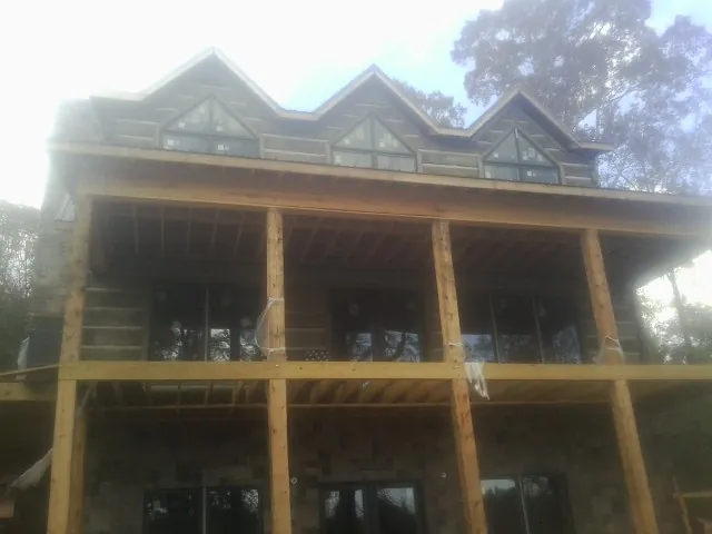 Dormers and porch framing on a large log home under construction — Roof Coating work by our crew in Shallotte