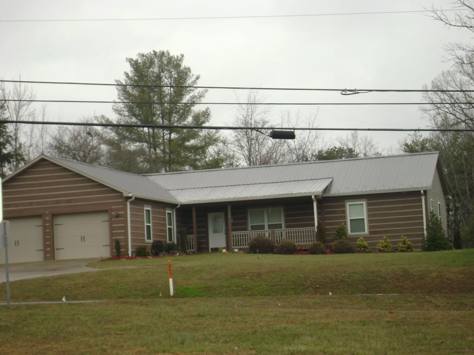 Gray metal roof on a log sided ranch home with a front porch in Shallotte