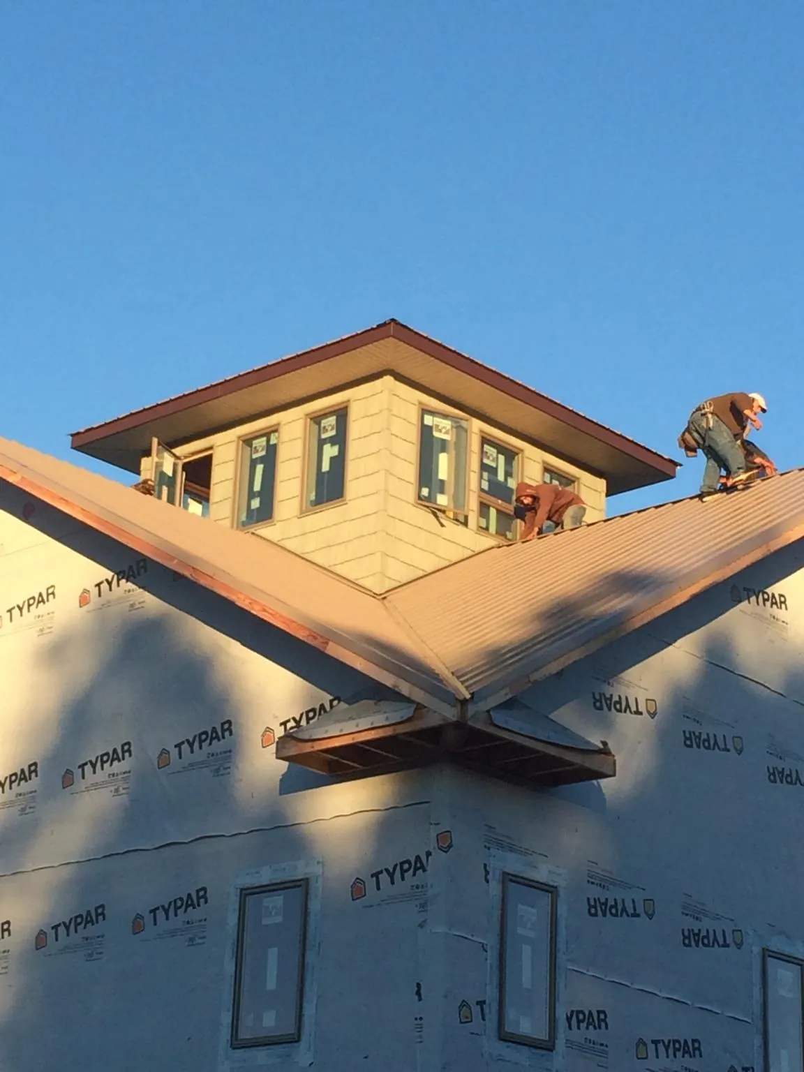 Roofers working around a rooftop cupola on a new metal roof at sunset — Roof Waterproofing in Shallotte by Roofing Brothers